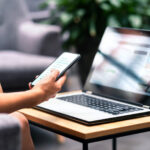 Woman using smartphone and modern notebook pc computer on table